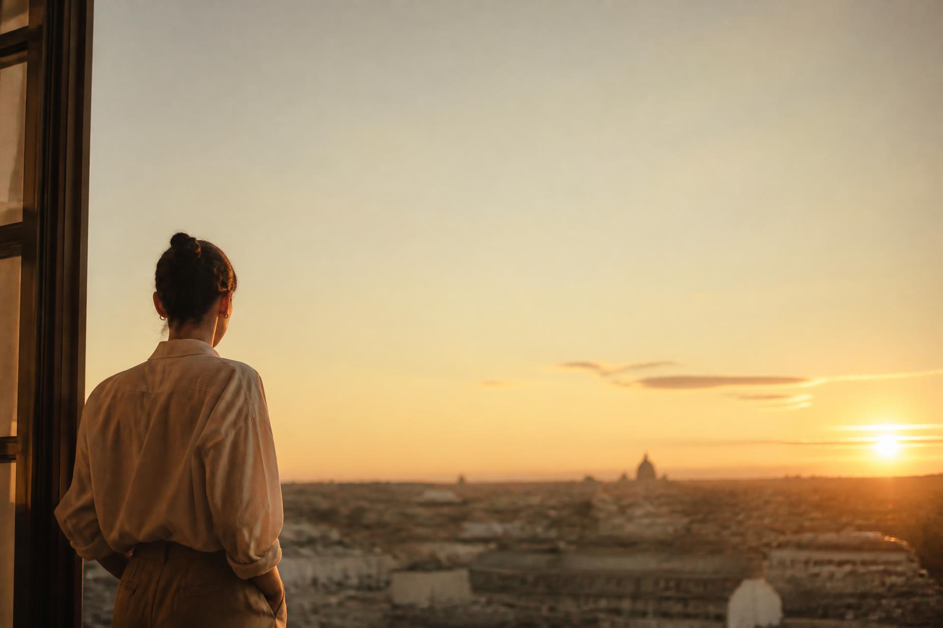 A person looking out at a warm horizon at sunrise, contemplating what's next in their career.